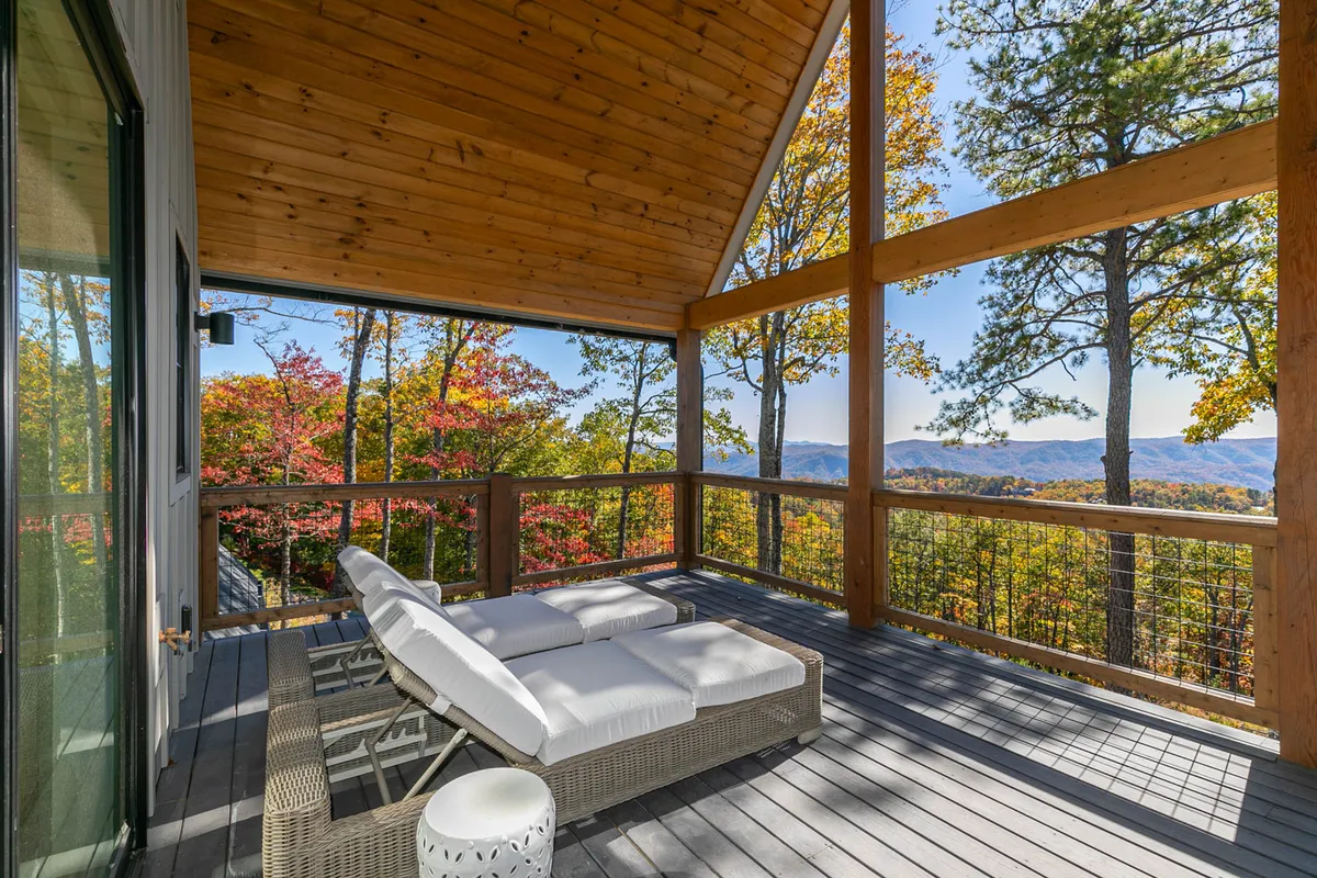 An inviting outdoor lounge area with wooden railings, lounge chairs, autumn foliage, and expansive mountain vistas. The scene is peaceful and open, ideal for relaxing after a day of adventure or simply soaking up the views.