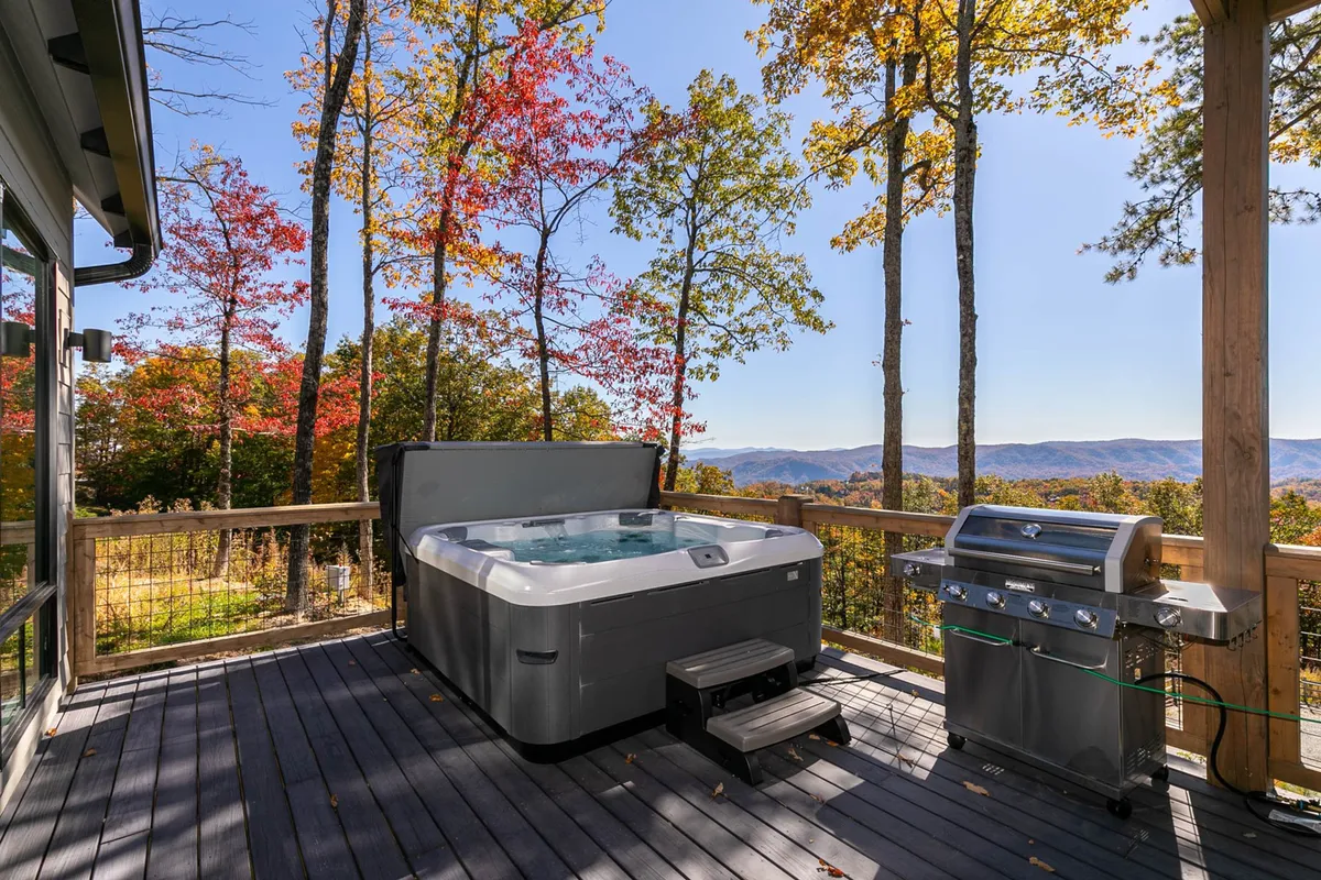 An outdoor hot tub area with a grill, offering scenic views of the mountains. The space is perfect for unwinding after a day of adventure, hosting barbecues, and enjoying sunsets in a tranquil mountain setting.