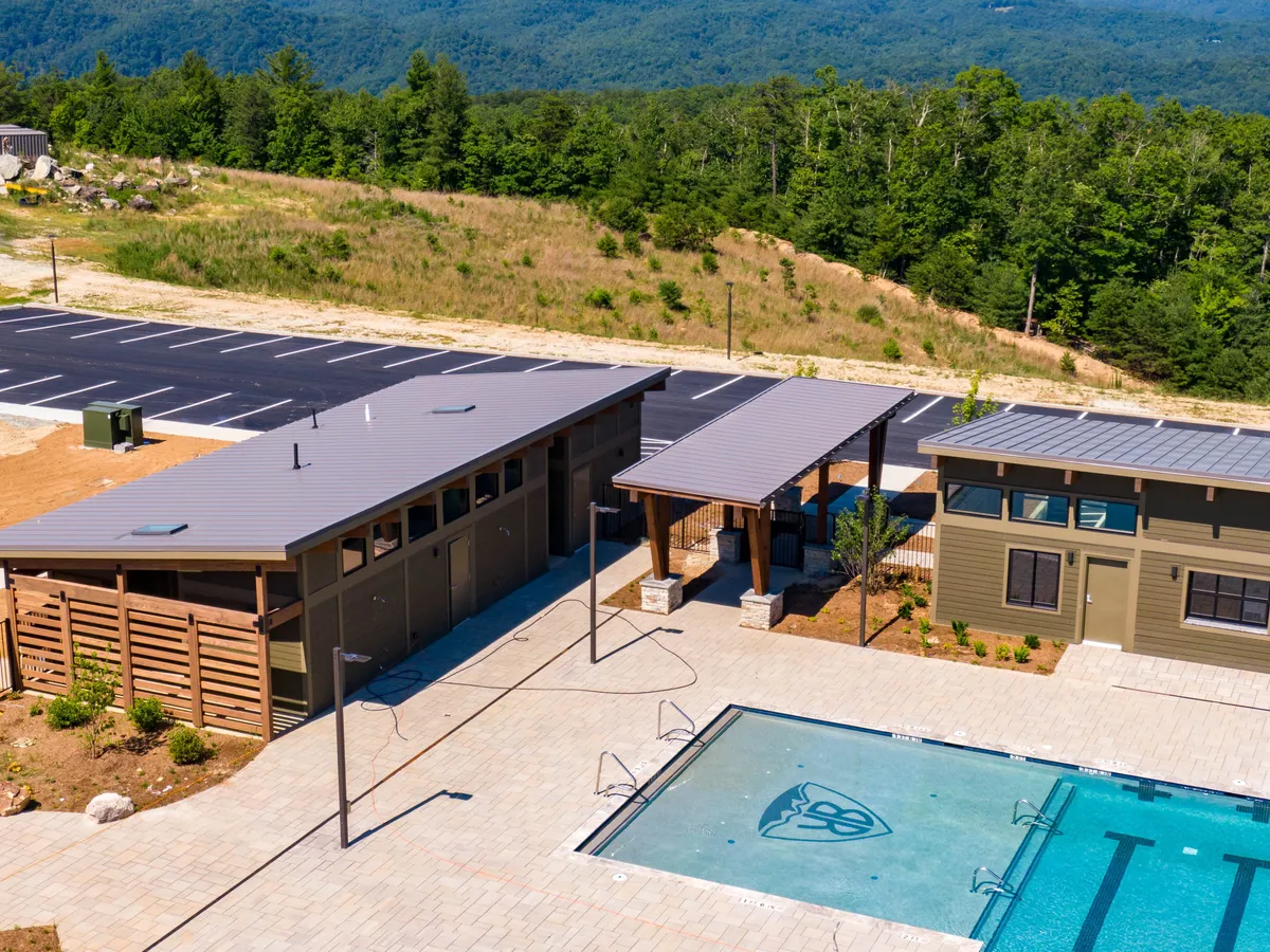 The swimming pool area is surrounded by lush landscape and features outdoor structures ideal for group activities. The open poolside creates a welcoming environment for socializing, relaxing, and hosting group events.