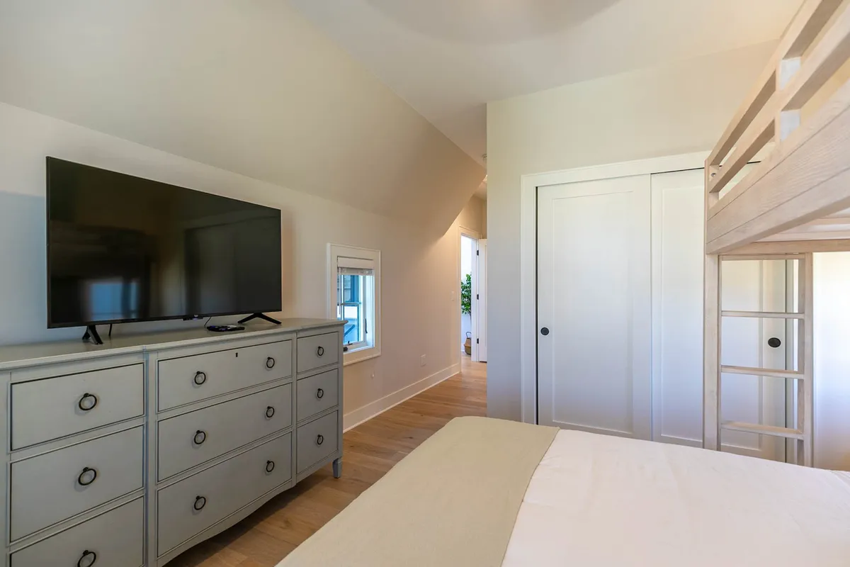 A cozy bedroom with built-in bunk beds, a TV atop a dresser, and a window letting in natural light. The room is designed for both relaxation and entertainment, making it ideal for families or groups traveling together.