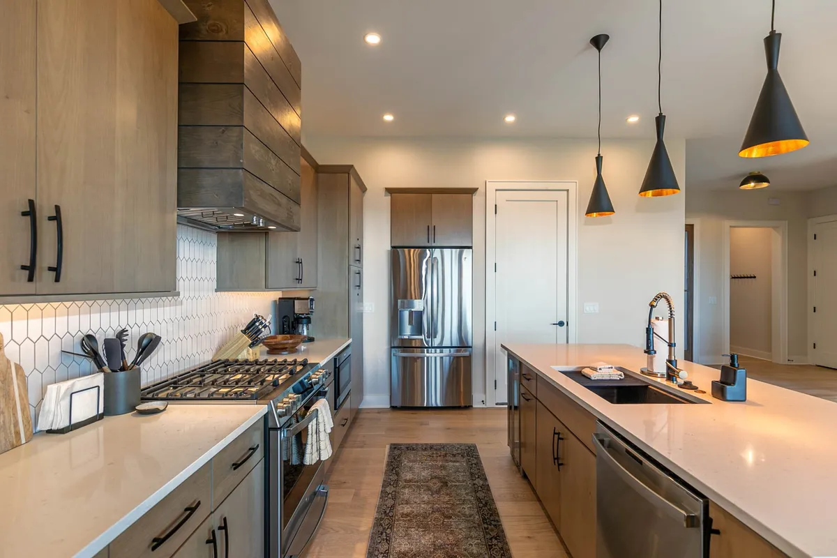 Contemporary kitchen interior featuring stainless steel appliances, a hexagon tile backsplash, and a prominent kitchen island. The space is set up for both solo culinary adventures and hosting friends for gatherings.