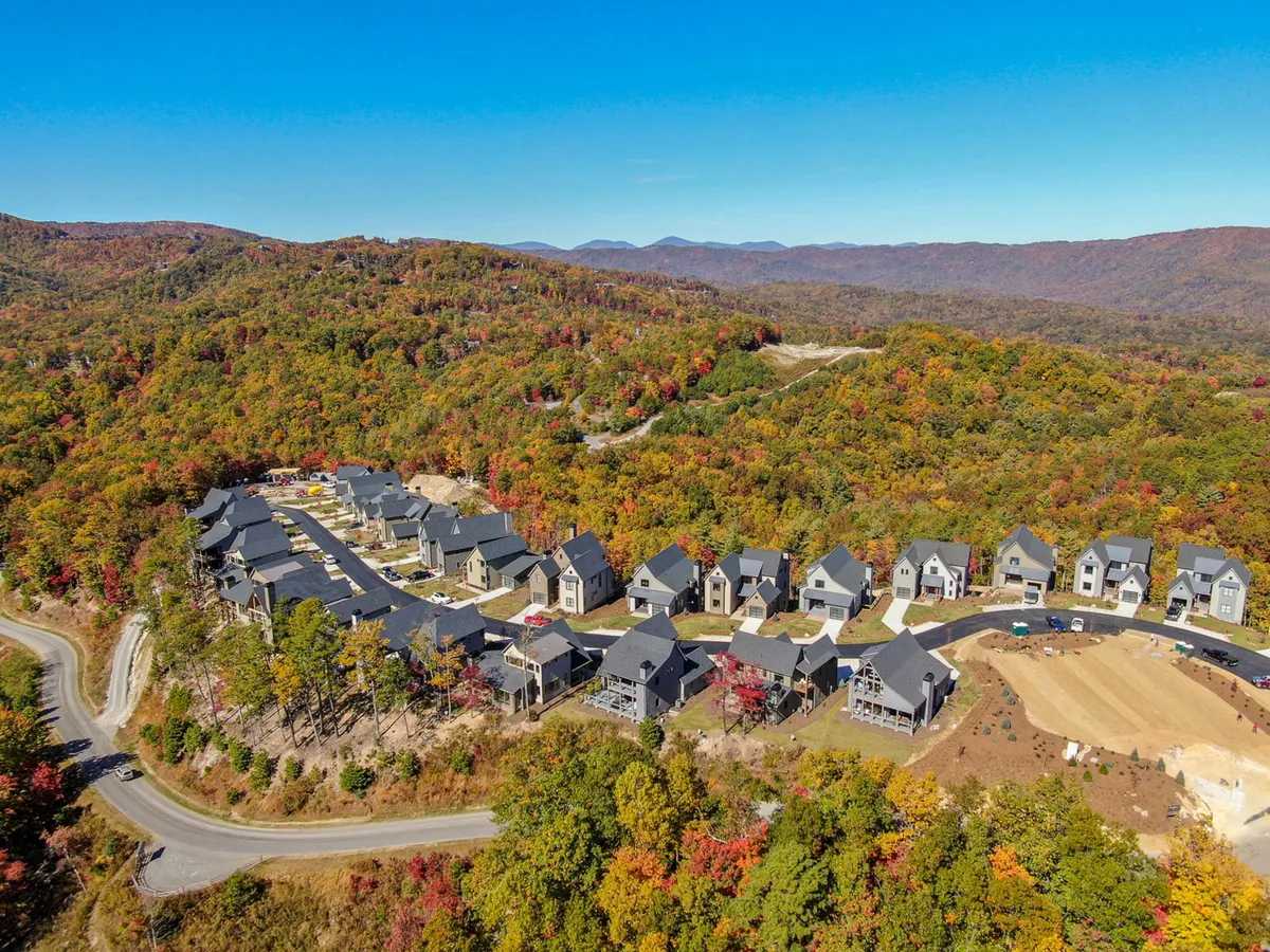 This image features modern homes nestled along a winding road, surrounded by vibrant fall foliage. The setting suggests a serene mountain community with easy access to nature trails and opportunities for outdoor exploration.