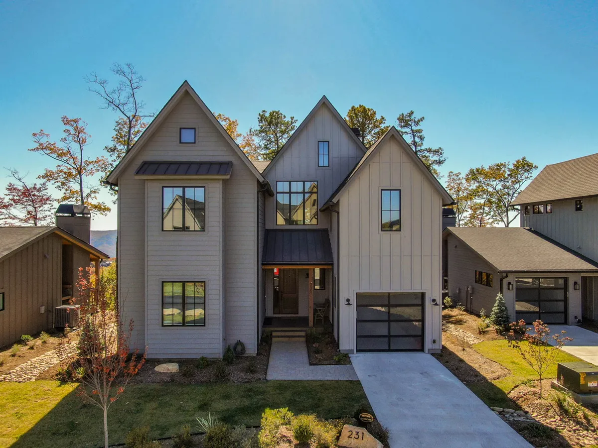 This image showcases the property's modern exterior with striking asymmetrical rooflines and expansive windows that reflect the surrounding landscape. The porch area invites gatherings, suggesting a space for groups to enjoy the outdoors together.